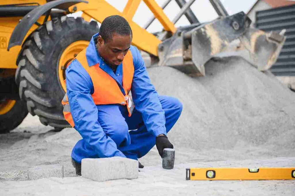 Construction worker installing concrete pavers with precision at a residential job site in North Royalton OH.
